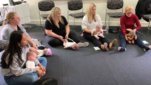 Students participating in infant massage instructor training using demonstration dolls