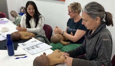 Students practising baby massage techniques on demonstration dolls during Brisbane face-to-face training course
