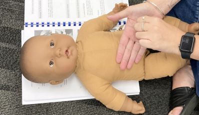 Close-up of baby massage technique demonstrated on a doll during Brisbane training session